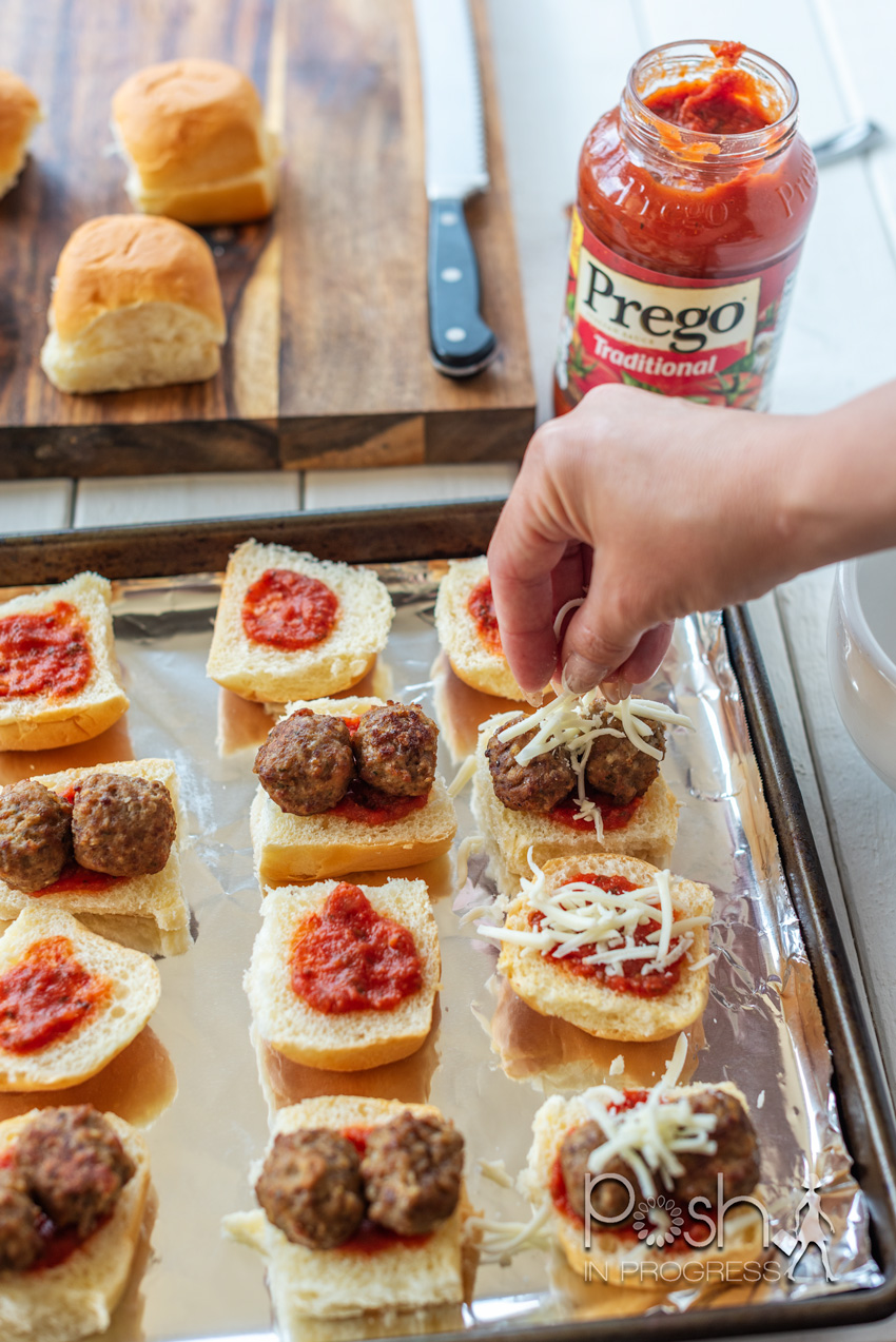 Meatball Sliders by popular LA lifestyle blog, Posh in Progress: image of a woman putting shredded mozzarella cheese on some meatball sliders a tin foil lined cookie sheet.