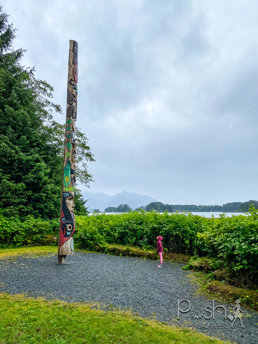 Things to do in Sitka Alaska by popular LA travel blog, Posh in Progress: image of a young girl looking at a totem pole.